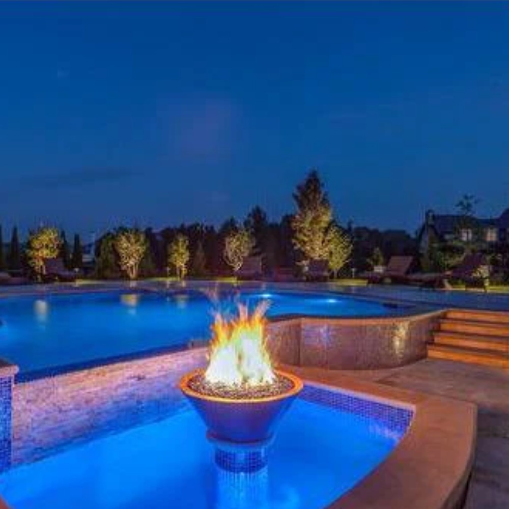 Copper round gas fire bowl with tall flames over blue glass media