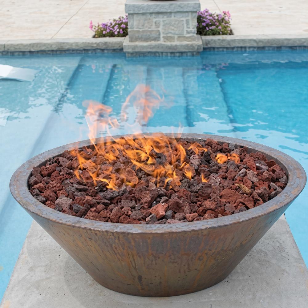 Round copper gas fire bowl with lava rocks and active flames