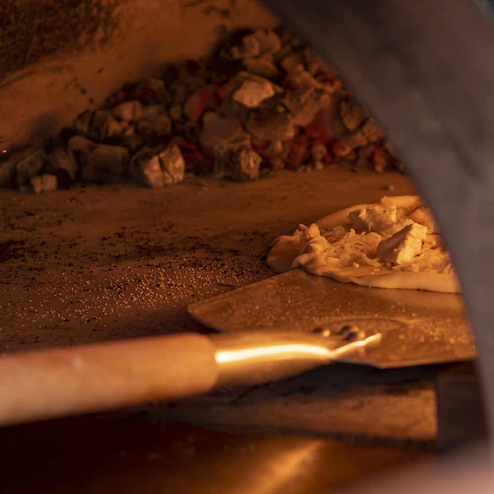 Aluminum pizza peel resting near the hearth while cooking pizza ingredients