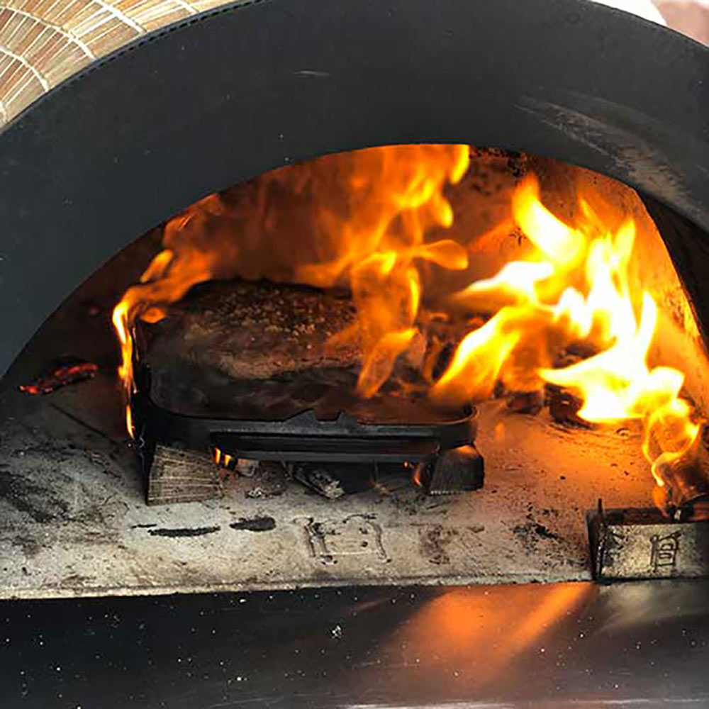 Pizza oven firebox with bright flames and black baking floor