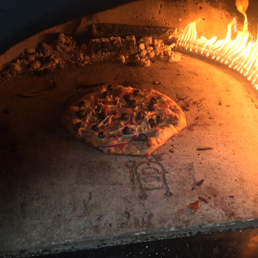 Pizza oven baking chamber with a pizza cooking near open flames