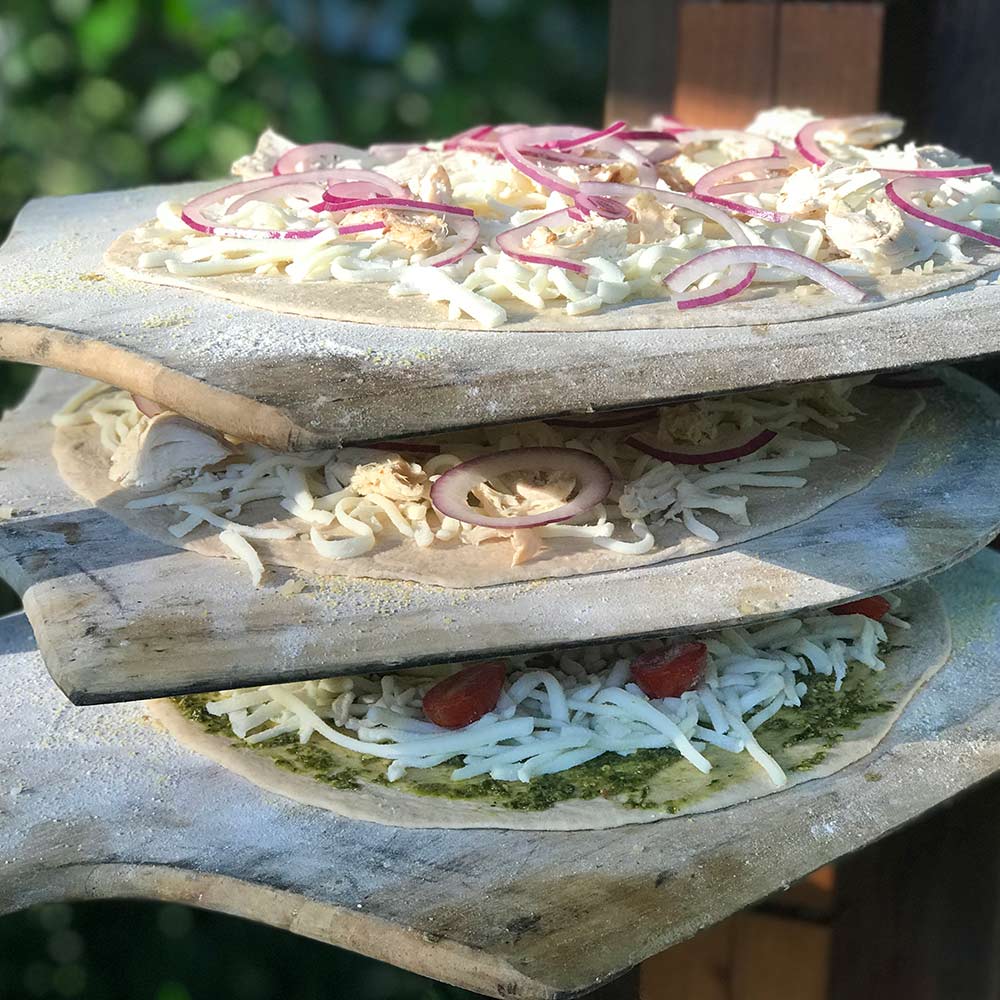 Wooden pizza paddle holding a topped pizza with onion slices and herbs