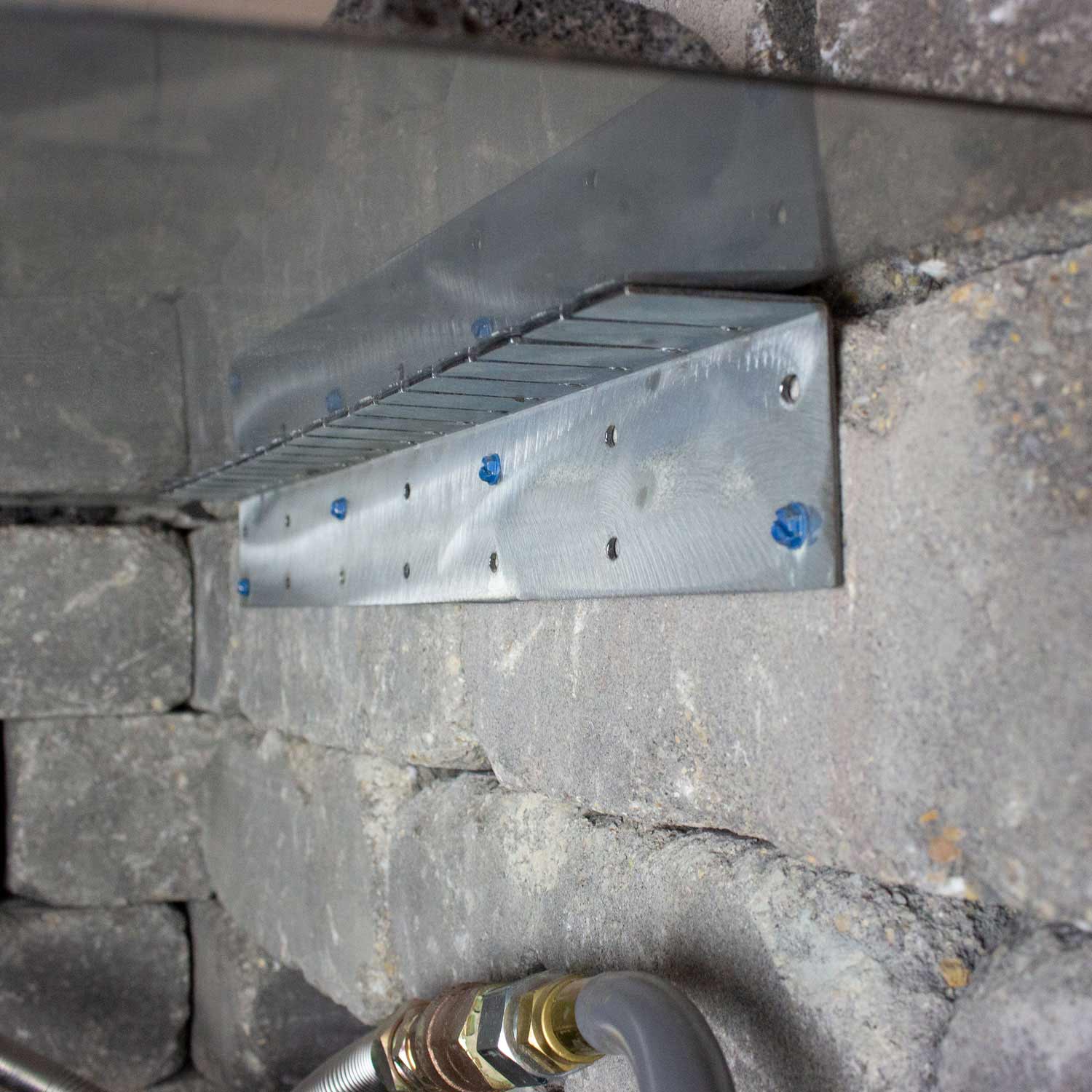 Flexible installation collar installed on stone wall, silver perforated plate with fasteners