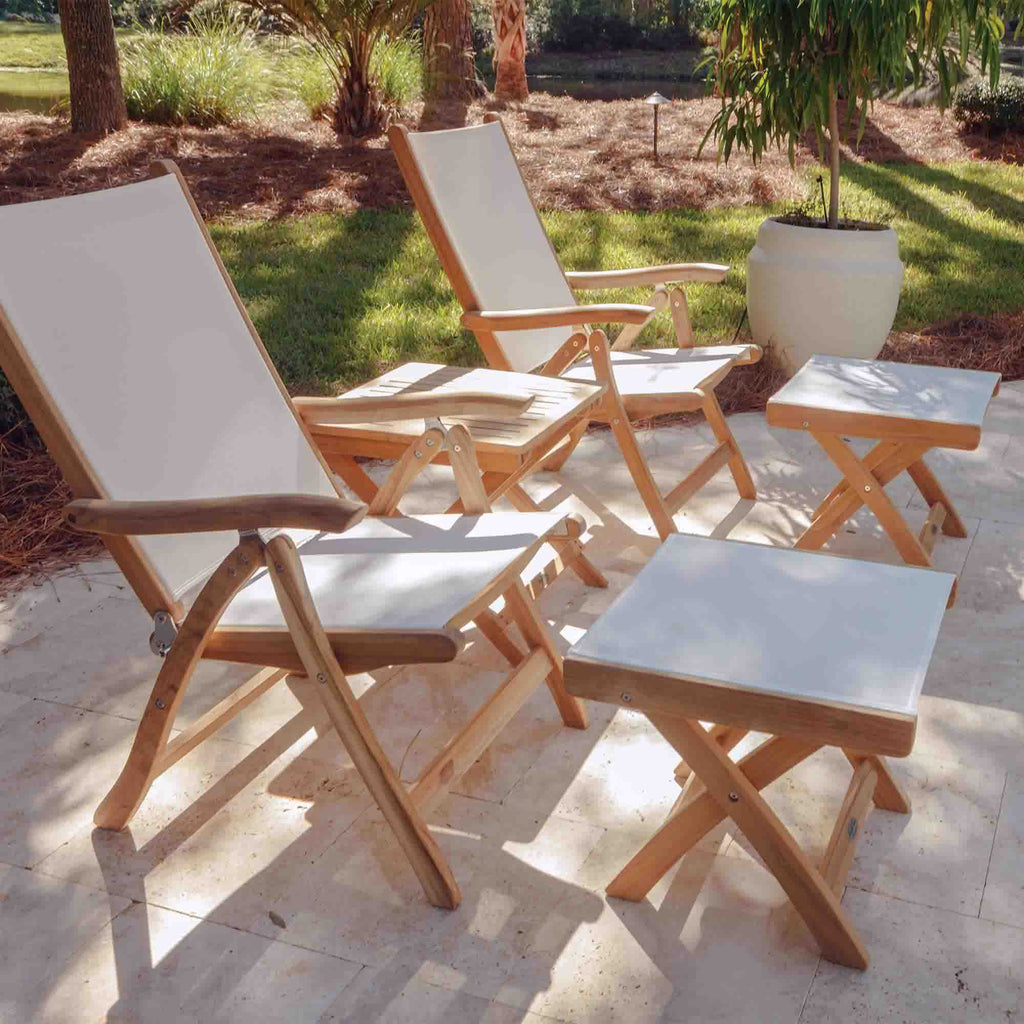 Outdoor teak sling chairs with light fabric seats and matching footrests