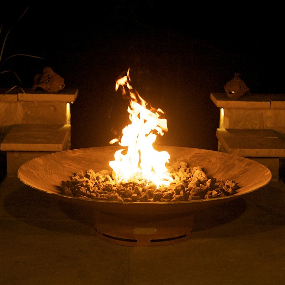Fire pit with tall open flame in a round metal bowl over lava rocks