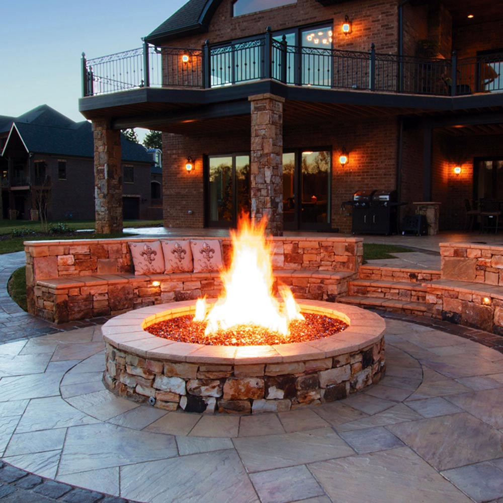 Circular stone gas fire pit with tall flame and round burner base