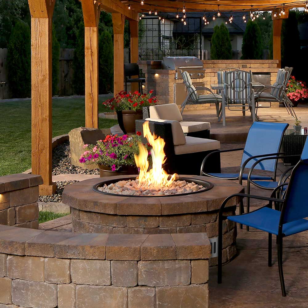 Outdoor gas fire pit with flame in a round stone base