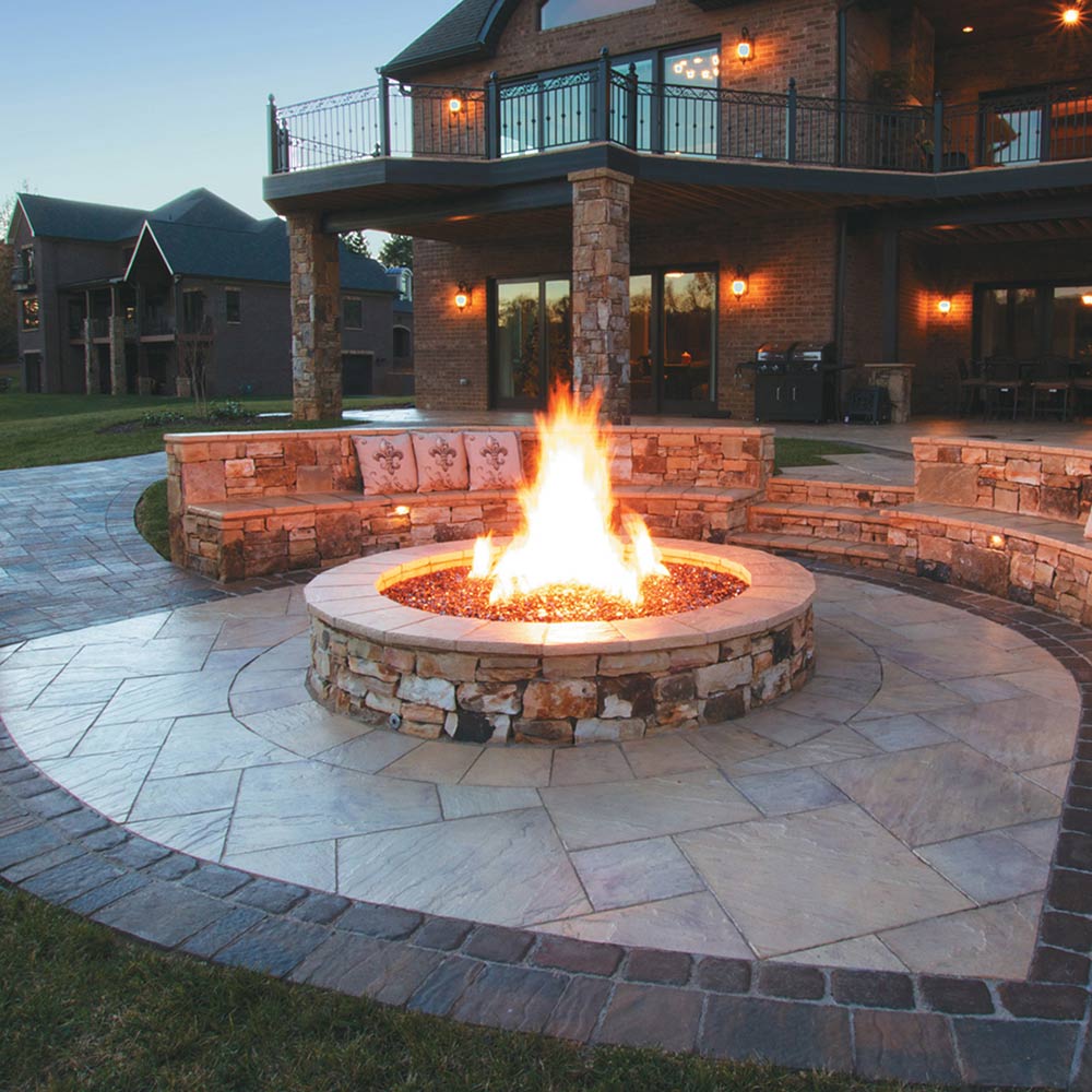 Outdoor circular gas fire pit with flame burning in the center bowl