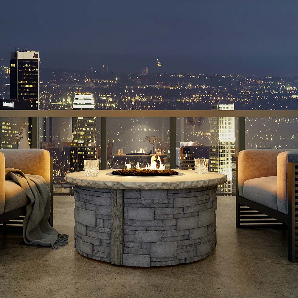 Outdoor tabletop gas fire pit with central flame in stone fire bowl