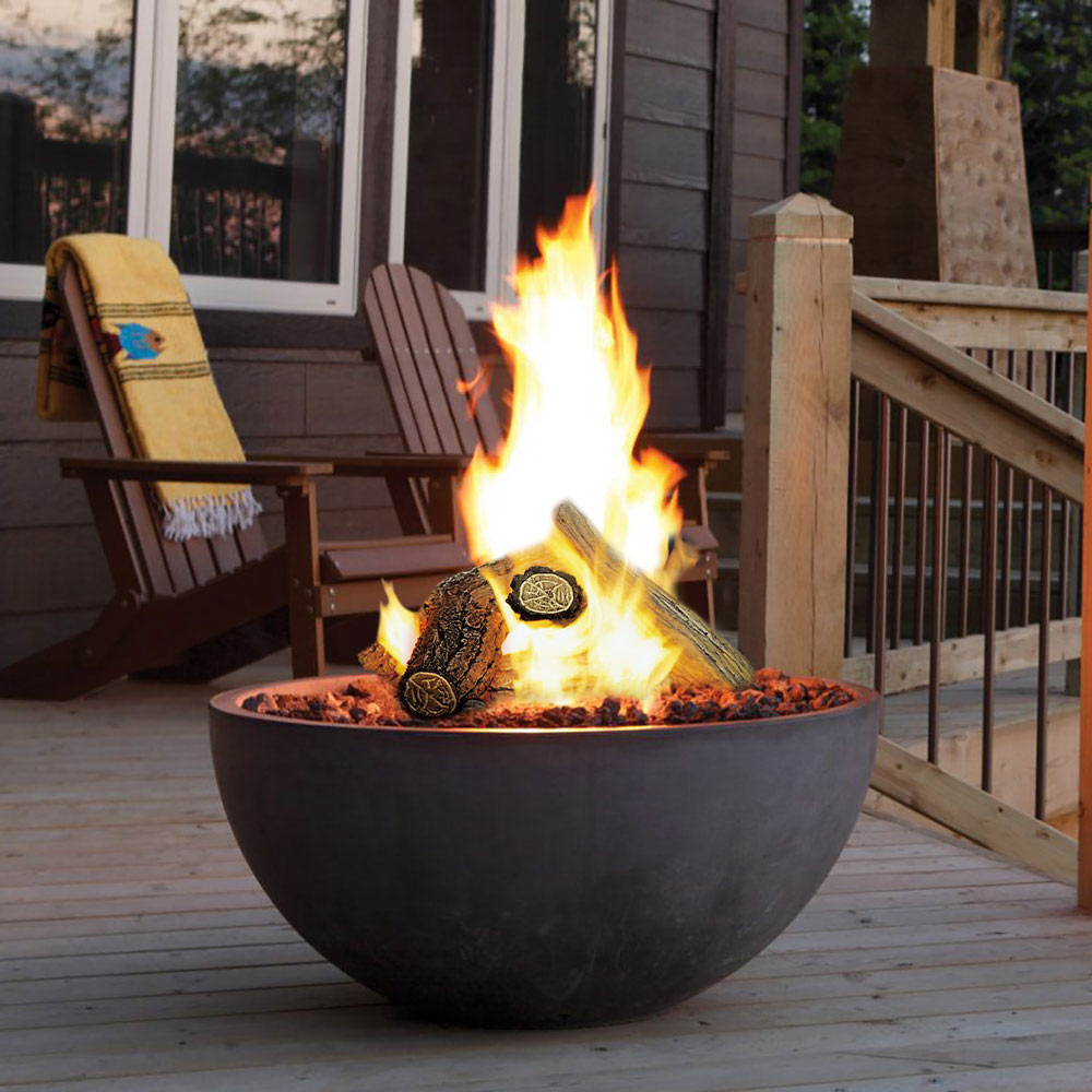 Round gas fire bowl with flames over lava rock and firelog pieces, dark gray