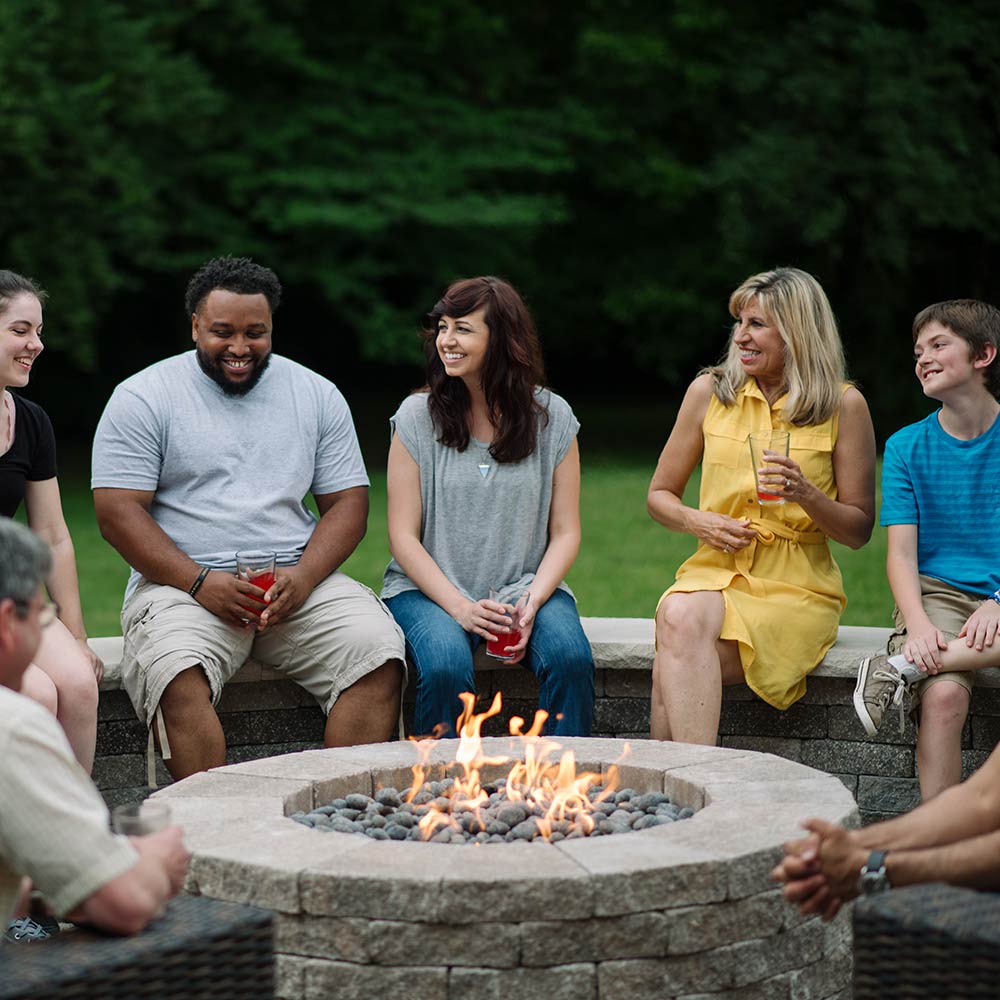 Round fire pit burner with visible flames in a stone fire pit bowl
