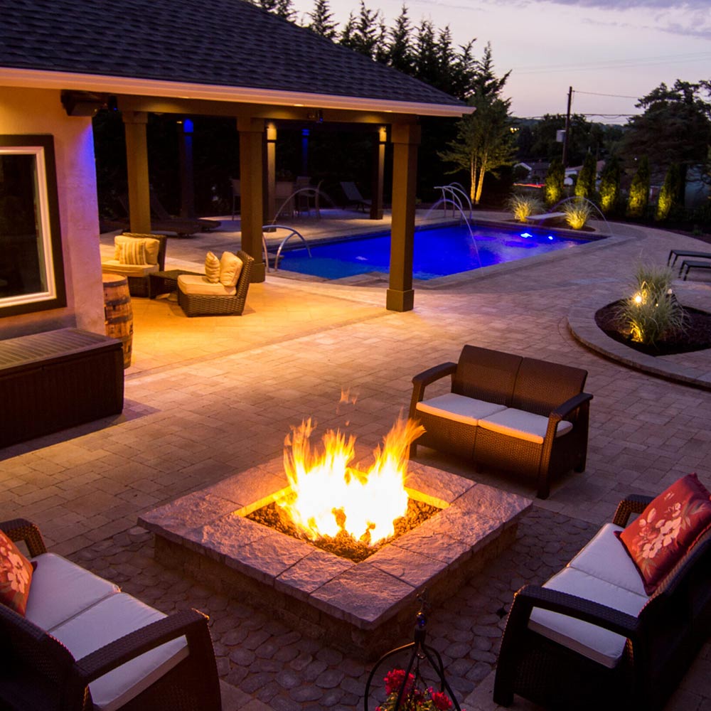 Outdoor square fire pit with visible flames in a stone surround