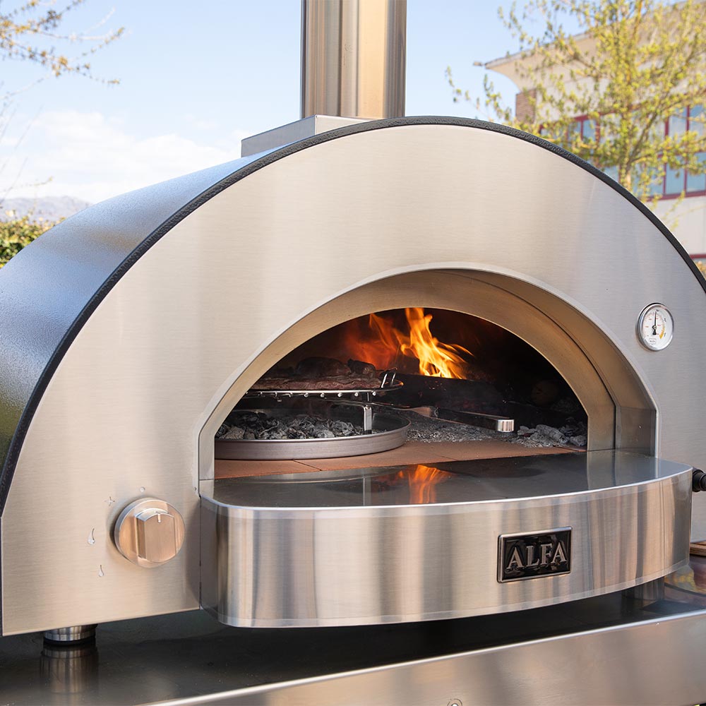 Pizza oven with open front door showing fire inside the stainless chamber.