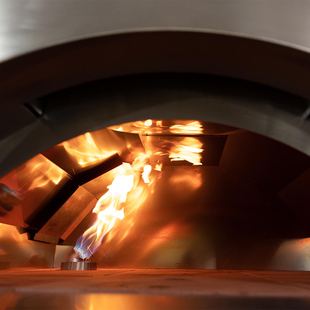 Pizza oven interior with active flames and heated cooking surface.