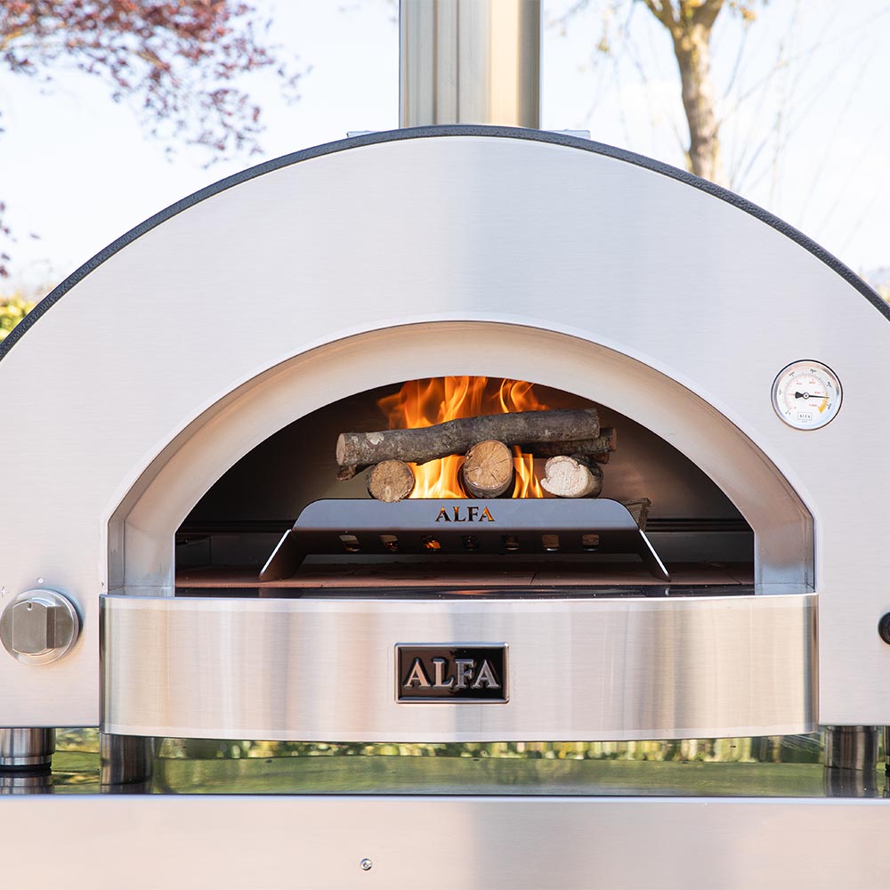 Pizza oven doorway with fire inside and stacked logs on the oven floor.
