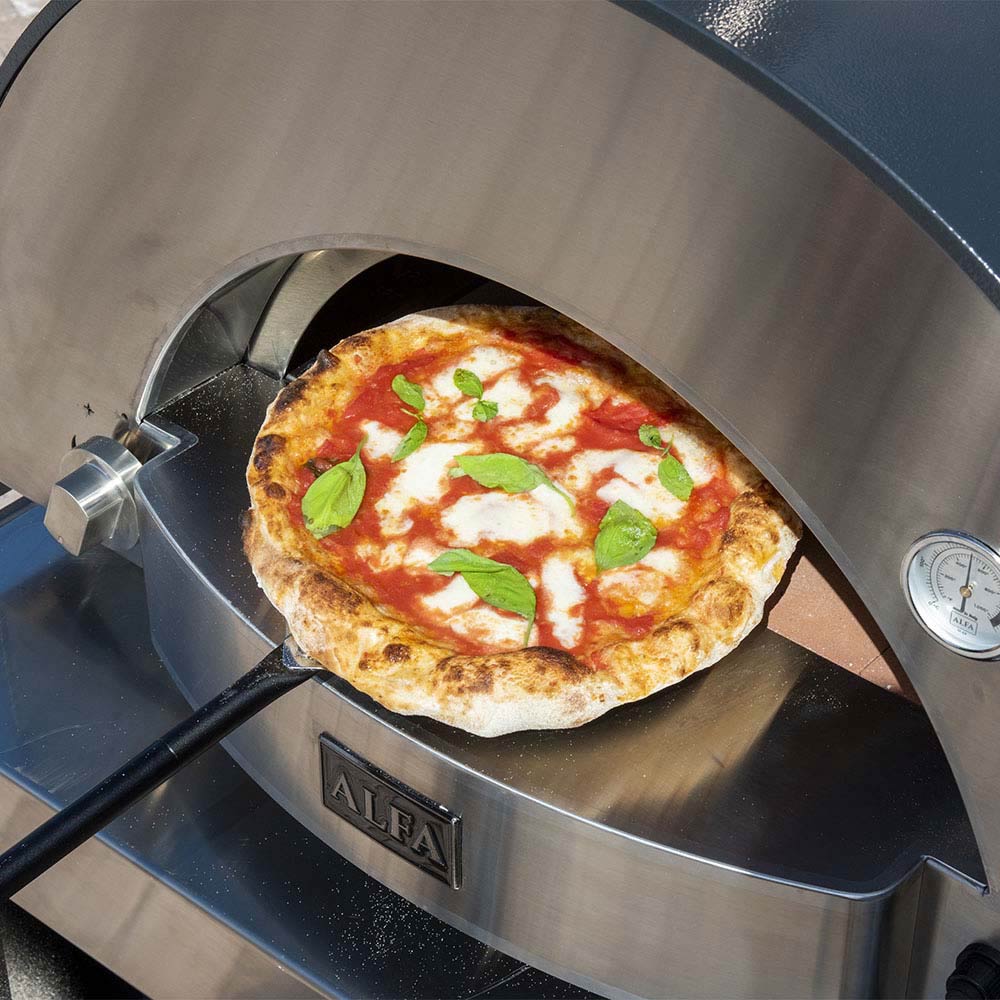 Pizza in the oven on the stone hearth with toppings visible inside.