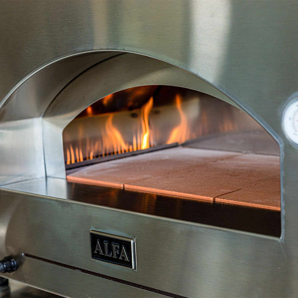 Pizza oven close-up of burning chamber, stone baking deck inside arched doorway