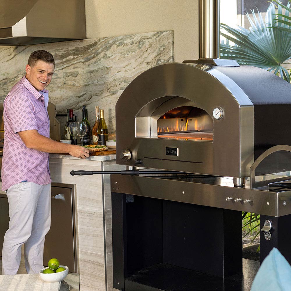 Stainless gas pizza oven with open dome and visible flames inside the chamber.
