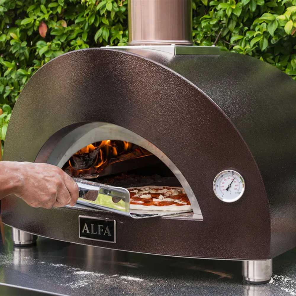 Gas pizza oven with hand using a peel to load pizza into the firebox