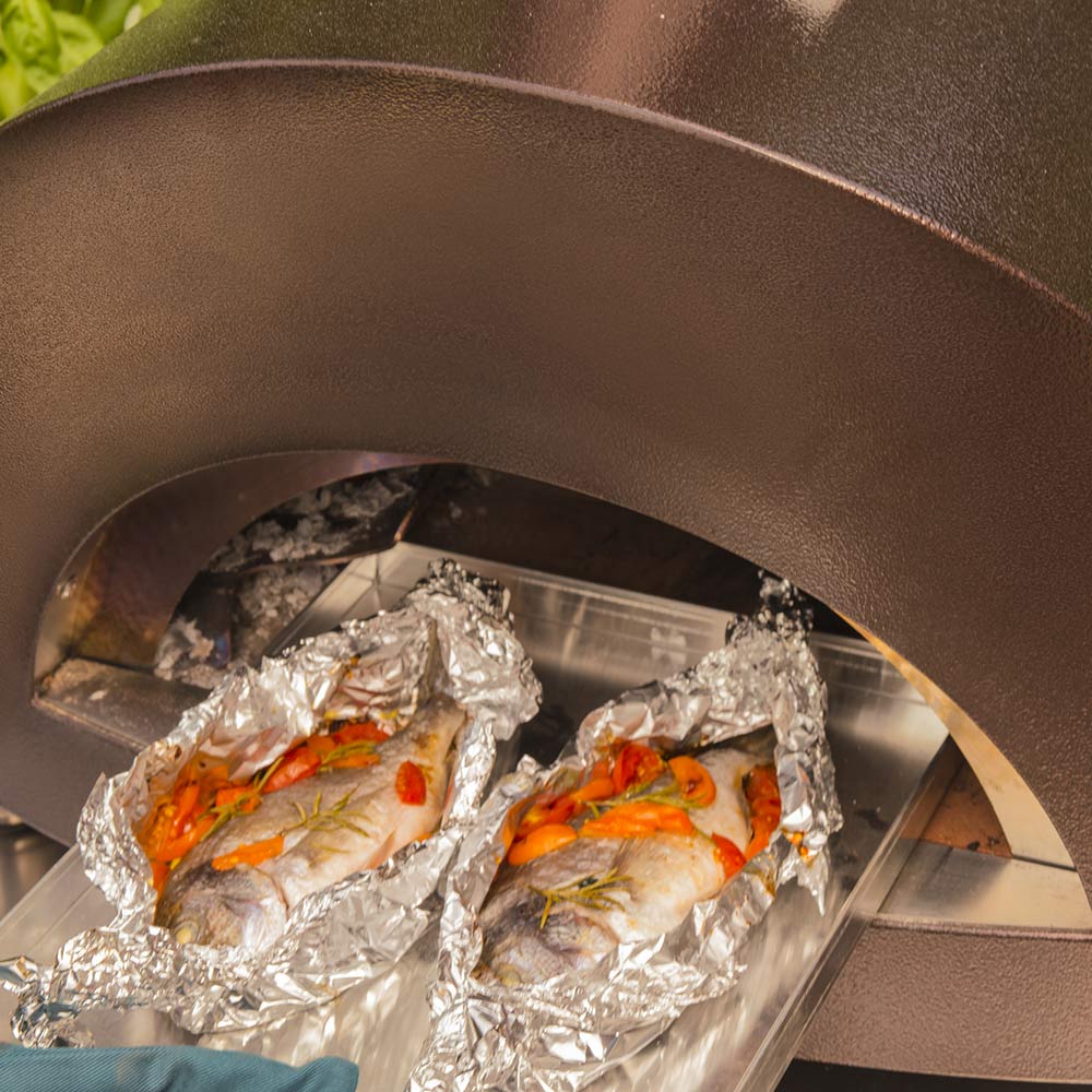 Foil-wrapped chicken and vegetables inside pizza oven chamber