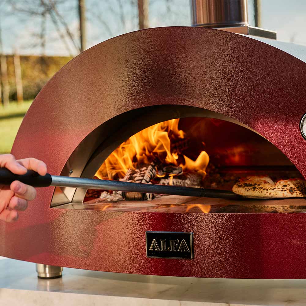 Wood-fired pizza oven with arched opening, red dome and visible flames inside