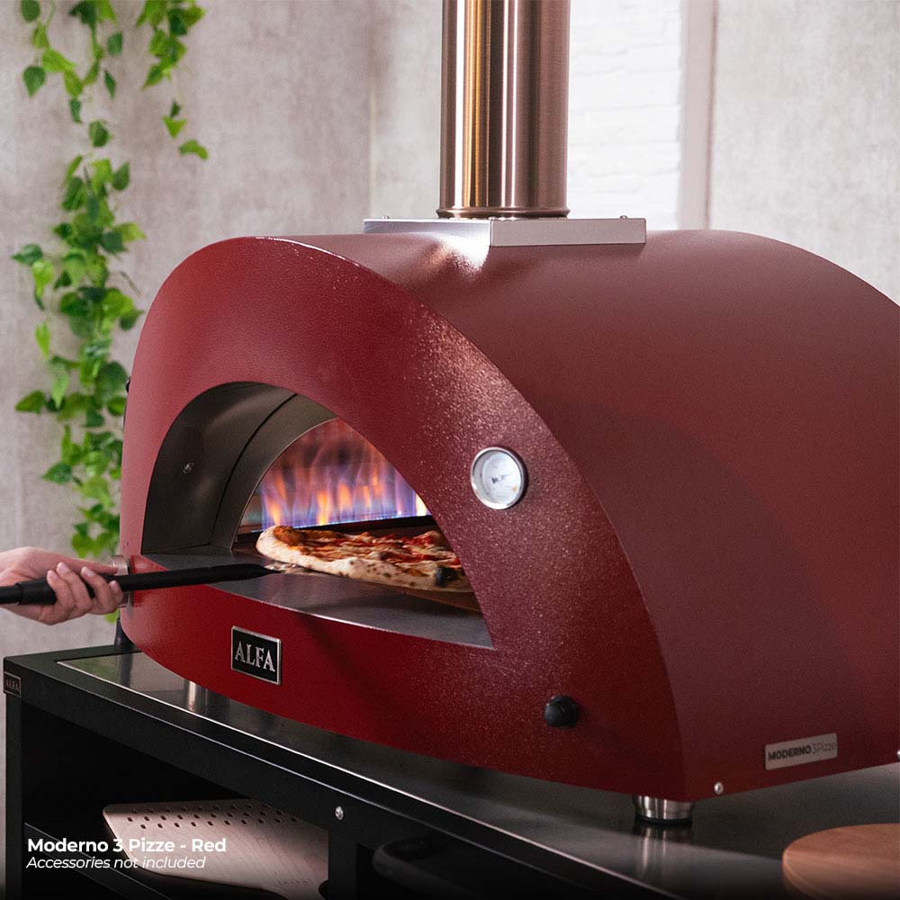 Ruby red gas pizza oven with arched opening, active flame, and pizza baking inside