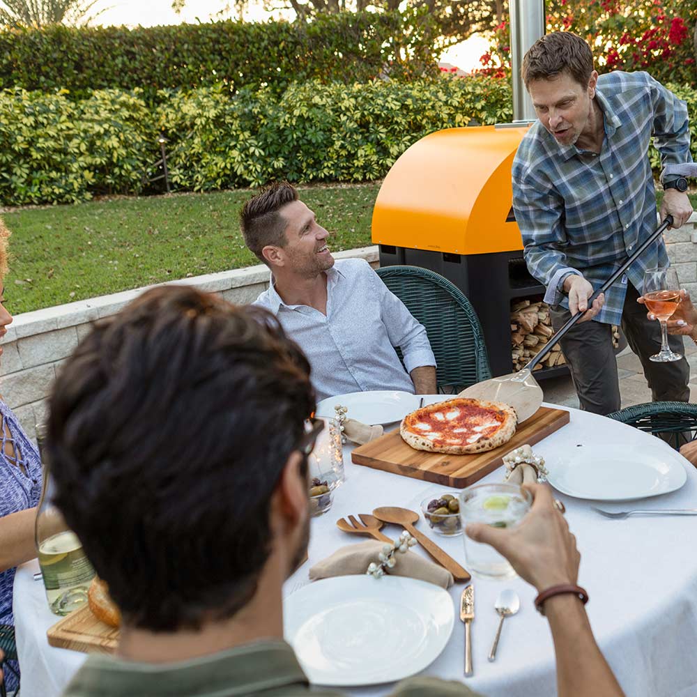 Yellow countertop gas pizza oven with stainless chimney near a prepared pizza