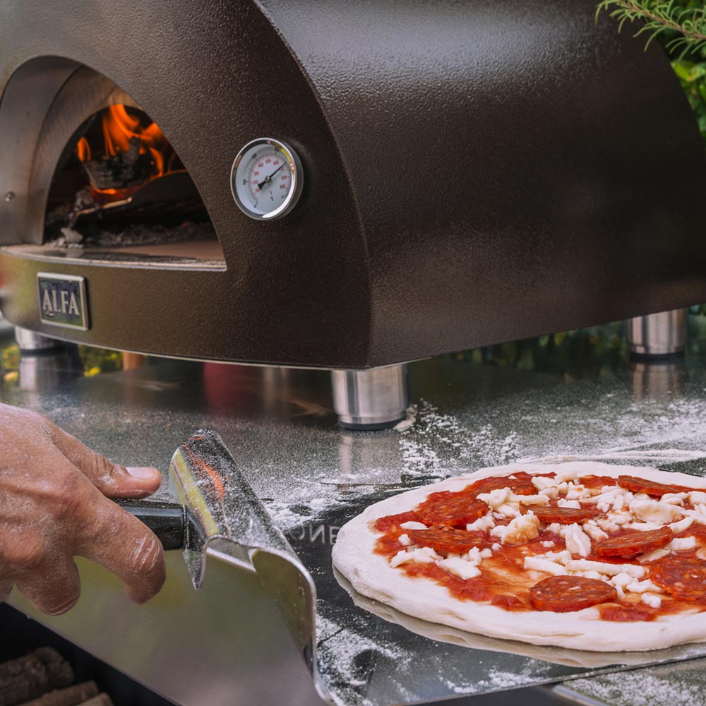 Wood-fired pizza oven with pizza baking on stone, flames visible through arched opening