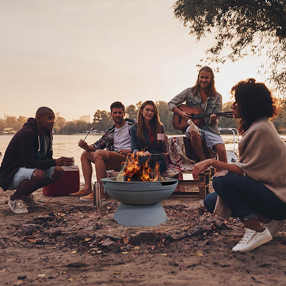 Portable fire pit with flames in dark gray bowl, set on outdoor ground