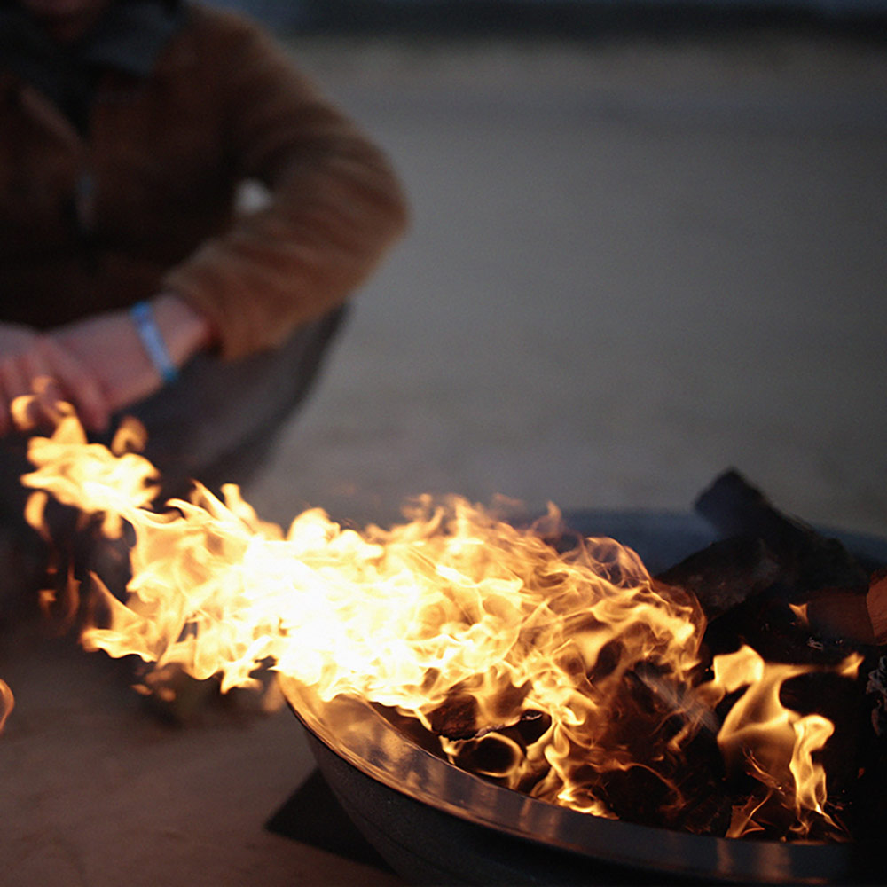 Wood-burning fire pit with close-up flames and dark gray burner pan