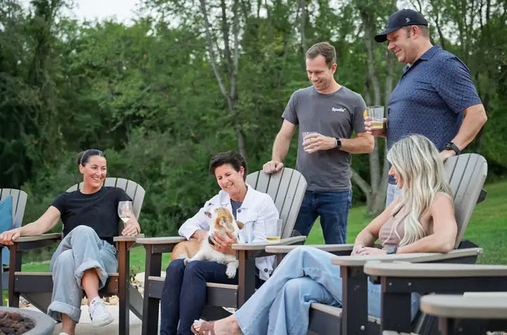 Group of friends and family relaxing around an outdoor fire pit on a patio