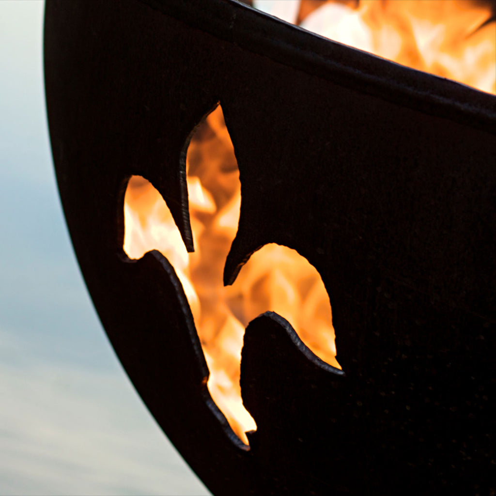 Close-up of gas fire pit metal cutouts with flames behind the pattern