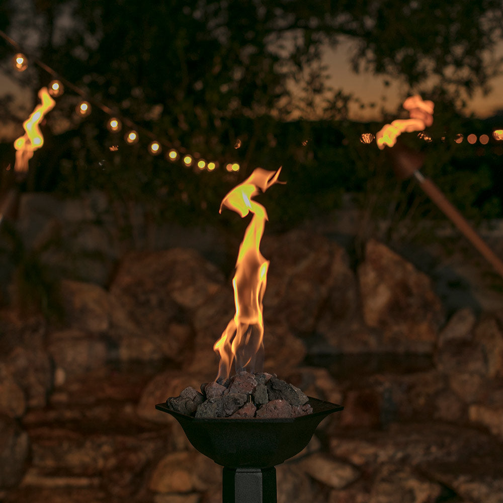Gas torch head burning with yellow flame in a black bowl