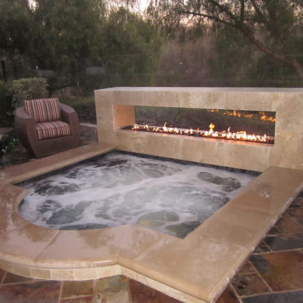 Stone outdoor gas fire pit burner with flames in a rectangular firebox