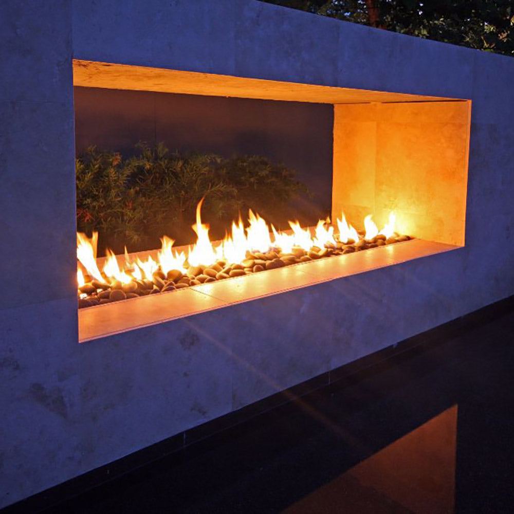 Modern outdoor linear gas fire pit burner with flames inside a wall niche