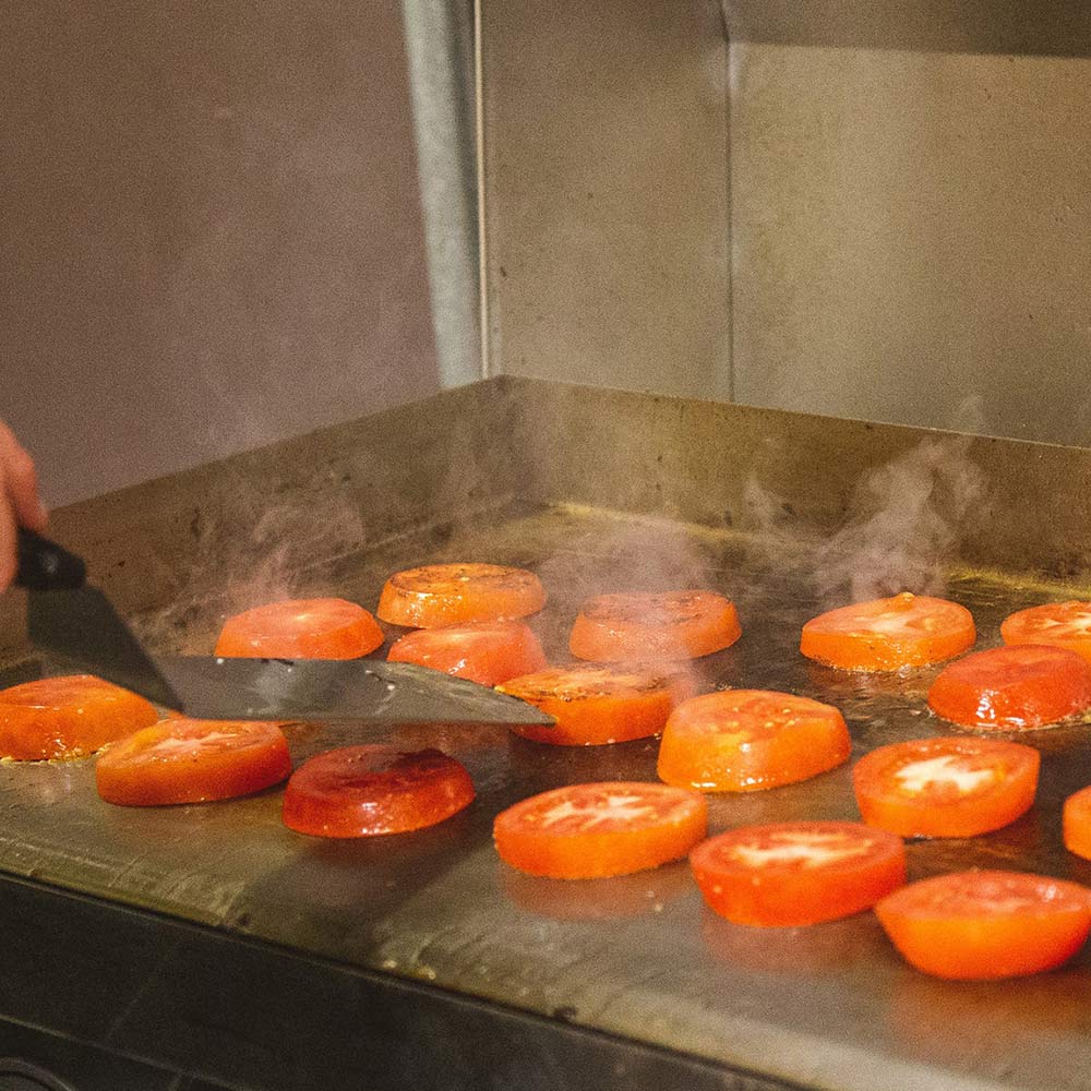 Electric griddle cooking surface with orange slices sizzling on metal surface
