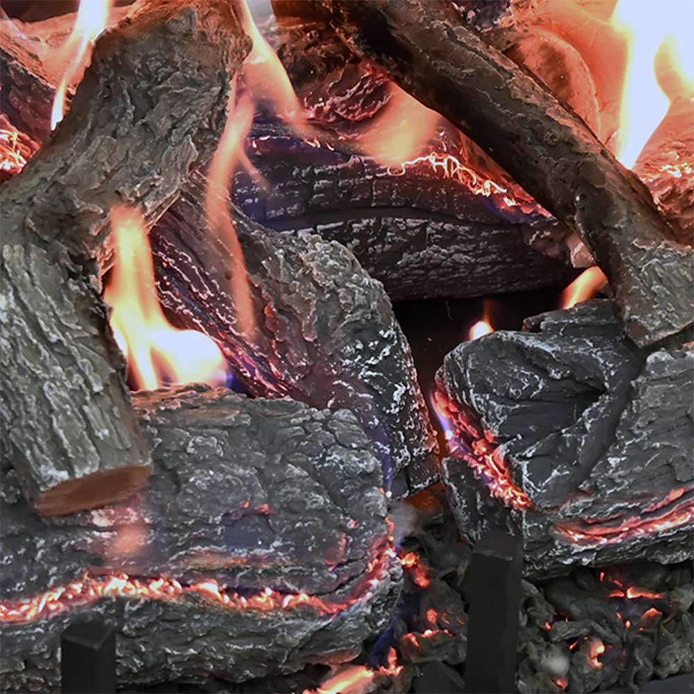 Charred gas log set with tall flames between dark logs and glowing embers