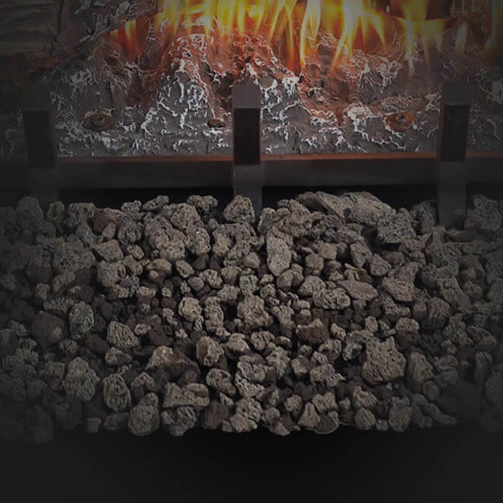 Ember bed of dark lava rocks in a vented gas log set firebox.