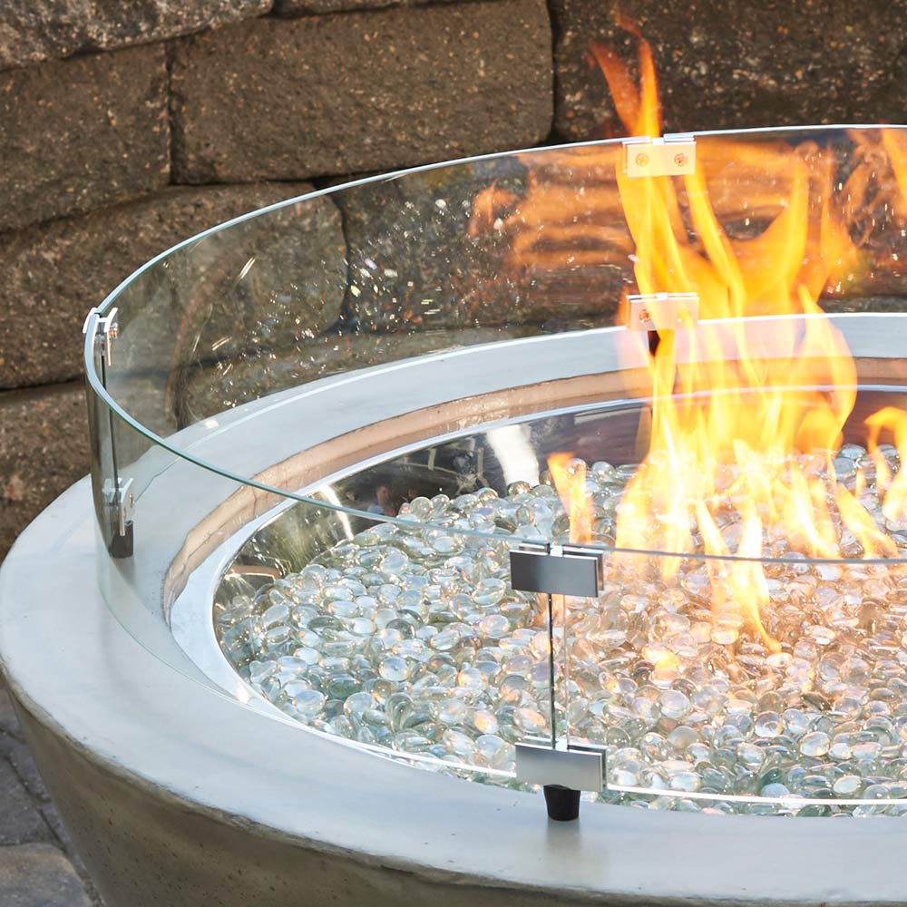 Round clear glass fire pit guard ring with black support brackets, with flames
