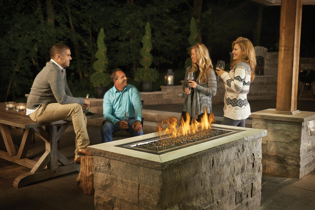Rectangular dark gas fire pit with flames in a stone outdoor base