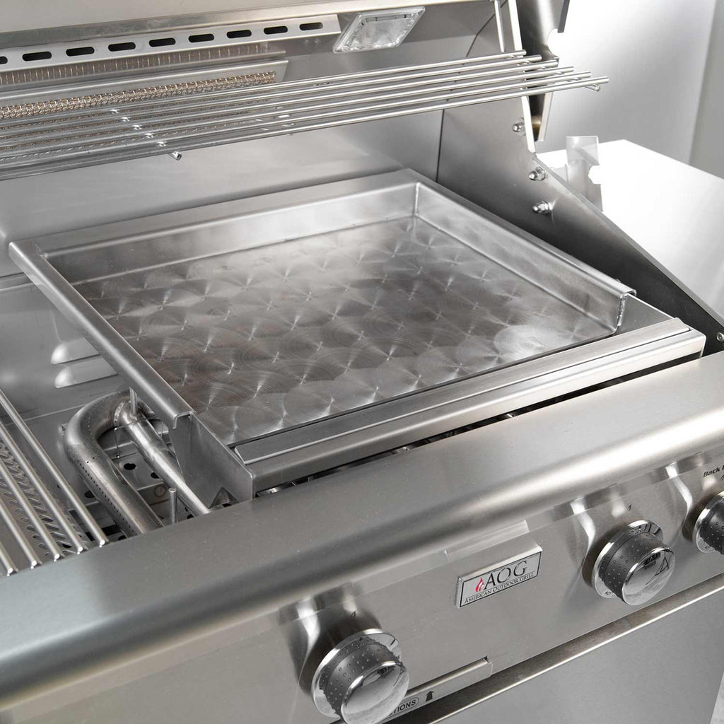 Outdoor stainless griddle tray with diamond pattern, set on a gas grill, front knobs