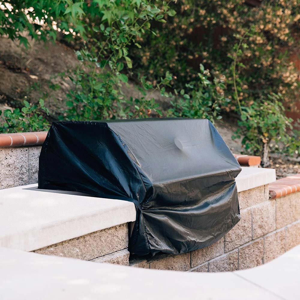 Built-in grill cover, black, covers a grill on an outdoor stone surround