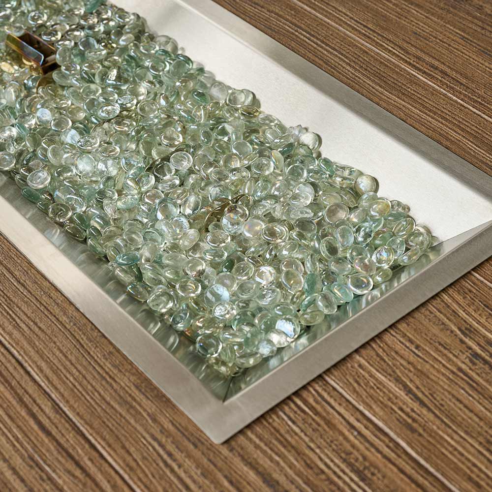Clear glass beads in metal burner tray on a wood-look tabletop