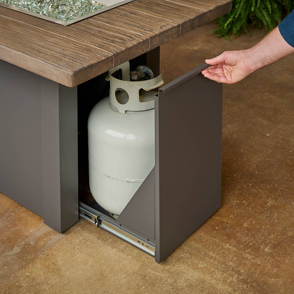 Open compartment of gas fire table with propane tank beneath the tabletop