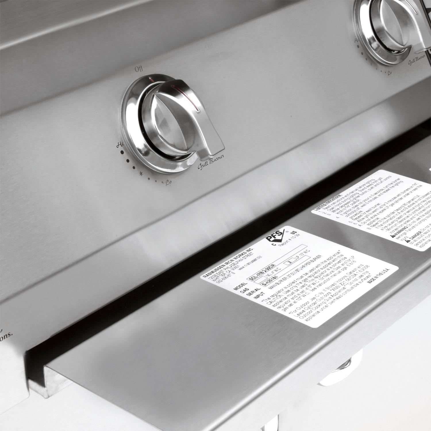 Stainless grill front control area with two knobs and safety rating labels