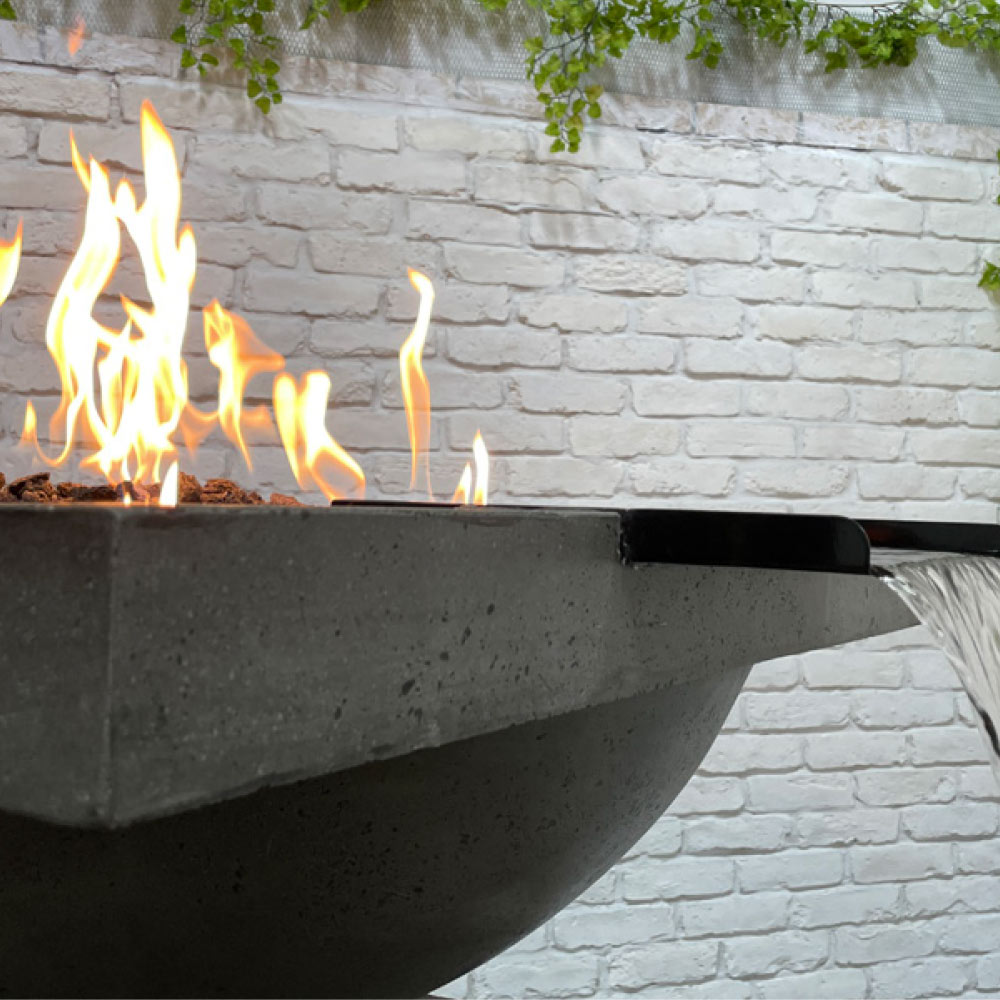 Outdoor concrete fire and water bowl with flames shooting up from burner