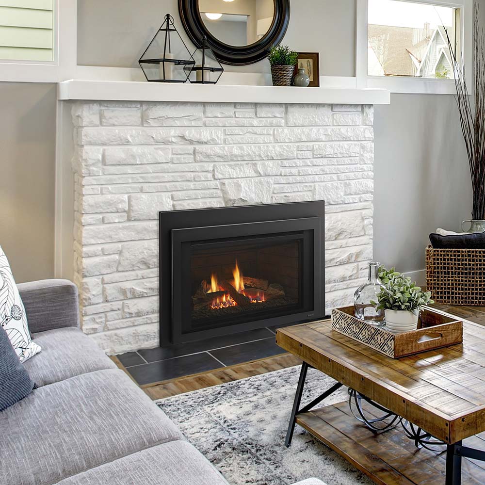 Black gas fireplace insert with glowing firebox flames in a stone wall surround