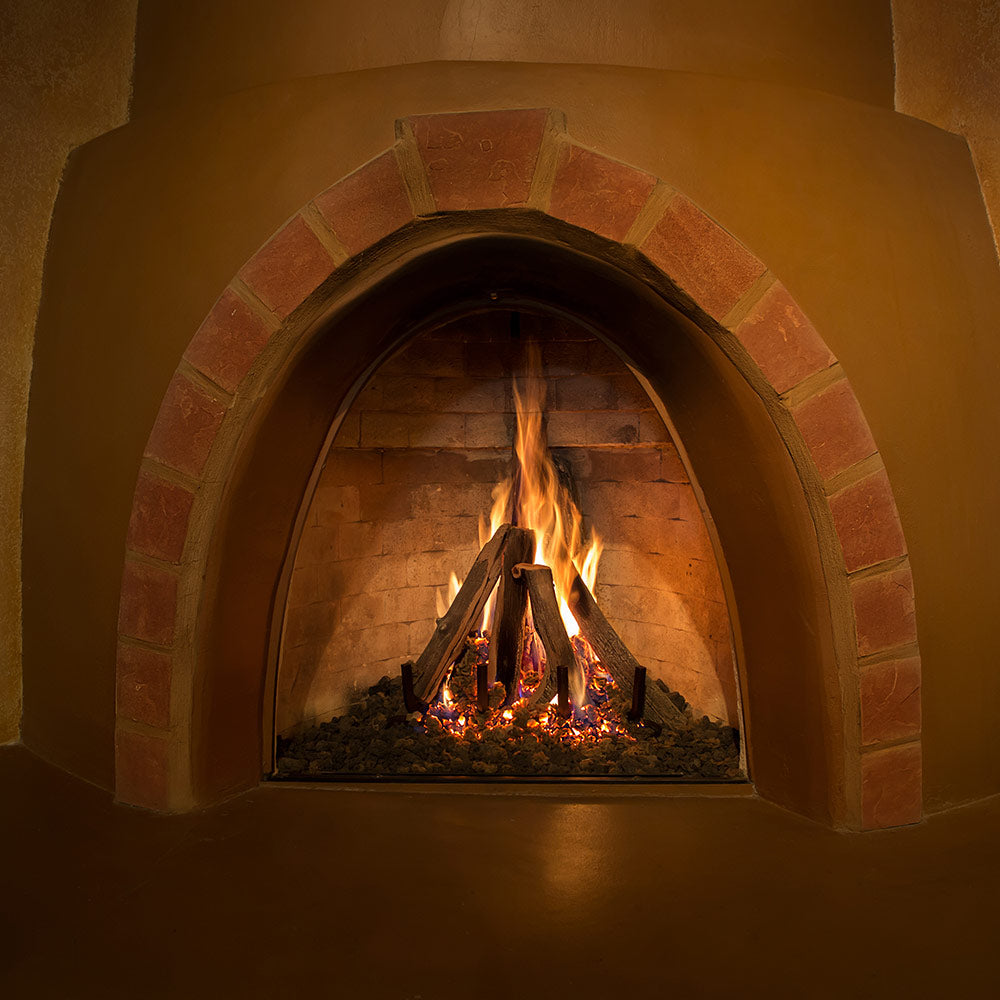 Vented gas log set with stacked logs, glowing embers, and open flames in a fireplace