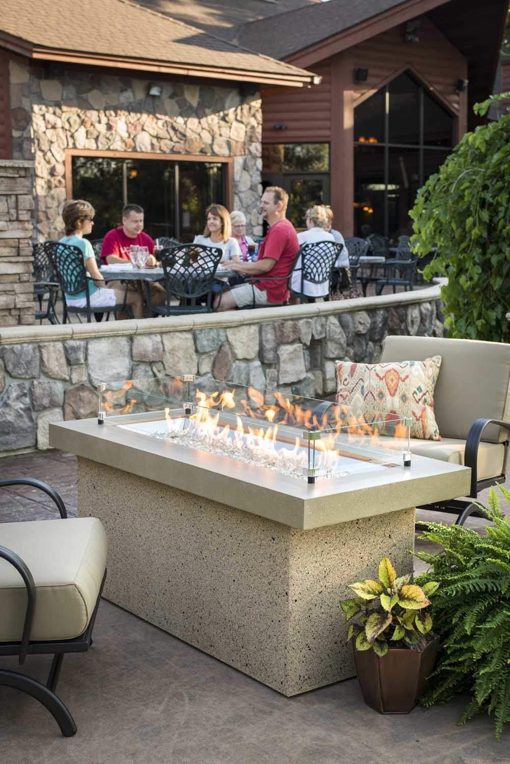 Rectangular glass wind guard on outdoor fire table, clear panels with metal posts