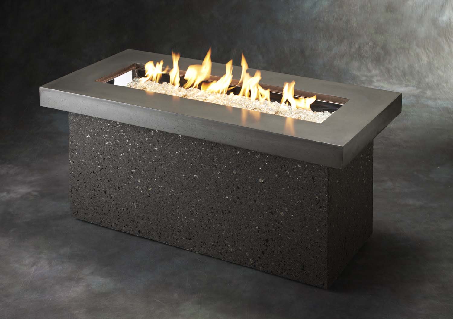 Outdoor gas fire pit with open flames and dark speckled base, rectangular black rim
